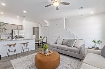 A modern living room with a grey sofa, a wooden coffee table, and a bar area.